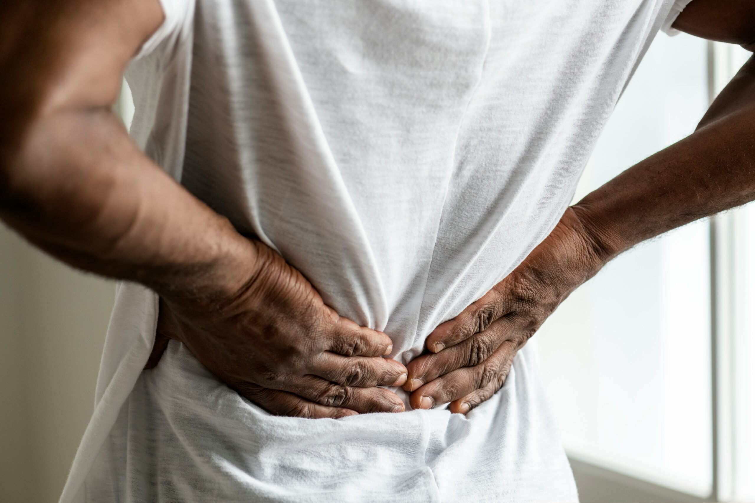 man gripping his lower back in pain